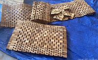 Photo showing stacked teak woven rectangular place mats and square coasters on a blue tarp.