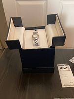 Open blue Concord box on table displaying watch on cushion with lot tag visible