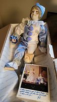 Full doll laid in box with Certificate of Authenticity showing below