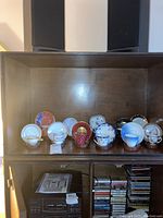 Shelved display of assorted demitasse cups and matching plates organized neatly on wooden shelf