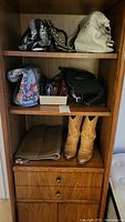 Handbags, wallets, wallets in tray, clutches and tan cowboy boots on shelf