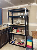 Front view of the metal shelving unit with 5 wooden shelves and various storage items placed temporarily on the shelves.