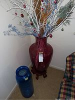 View of both vases: pink vase with stand and branches, and blue Blenko vase