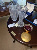 Photo showing both Waterford Crystal vases with distinct cut patterns along with the open gold-toned trinket box holding cubic zirconia crystals on a round table.