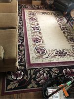 View of the floral and leaf themed area rug in living room setting next to furniture.