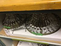 Two crystal ceiling light fixtures placed on foam padding in a storage shelf. Both fixtures have metal frames with hanging crystal prisms in a tiered design.