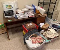 Fabric, sewing supplies, plastic storage bins, pillows on and around desk