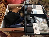 Opened TensPlus Dual Channel Stimulator Kit case showing charger, manuals, box of accessories, and battery pack.