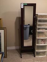 Full view of the dark wood framed standing floor mirror with reflective surface, showing pivoting mechanism on the side and base support.