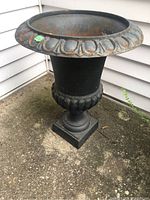 Full view of metal planter showing overall condition and decorative base.