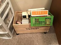 Vintage Singer sewing machine, green basket labeled 'Things' with accessories, and buttonholer box seen inside wooden crate.