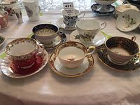 Front view of six assorted fine bone china tea cups and saucers showing various floral and gold trimmed designs from Royal Albert, Aynsley, Royal Ascot, and Royal Paragon by Appointment
