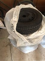 Four Michelin tires stacked, each mounted on steel rims, sitting wrapped in plastic.