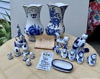 Full display of two floral porcelain vases, animal and female figurines, and small oval bowl on outdoor table.
