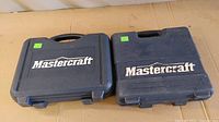Two black plastic carrying cases with Mastercraft labeling, containing cordless drills and accessories.