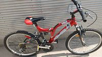 Full side view of red and black bicycle showing frame, wheels, saddle