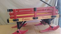 Side view of the Express Wagon showing red wooden slat sides with natural wood base and pink ski attachments instead of wheels.