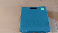 Closed blue hard plastic Makita carrying case on cardboard surface.