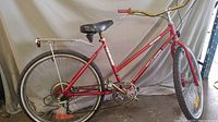 Full side view of the red 26-inch girls' Nevada Velo Sport bike showing the frame, saddle, rear luggage rack, tires, and some rust spots.
