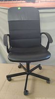 Front view of the black office chair showing the padded seat and backrest with armrests.