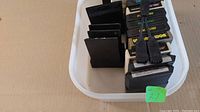 Lot of 16 Atari and Coleco game cartridges in plastic bin, viewed from top showing labels and connectors
