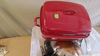 Red KitchenAid rectangular roaster with lid on top and other cookware visible below