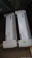 Two white Noma space heaters placed horizontally showing side profiles and front vents.
