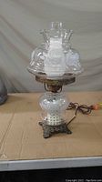 Full view of vintage electric table lamp with clear etched floral glass shades and bronze metal base.