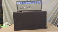 Front view of Traynor amplifier head on top of speaker cabinet, showing full front face with control knobs and logo.