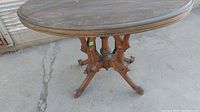Full view of the oval wooden table showing the tabletop and decorative base with claw feet.