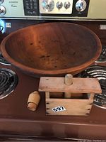 Top view of the large wooden butter bowl with butter mould and stamp placed inside on the stove top.