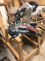 Front view of Bosch 3915 sliding miter saw on wooden stand showing blade and fence
