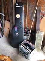 Black Fender hardshell case upright next to wall, record crate at base