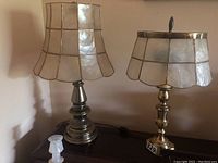 Two brass table lamps together showing overall size difference and lamp shade shape.