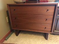 Front view of walnut-veneer dresser showing three drawers and black peg pulls