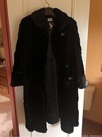 Black vintage mink coat hanging, showing full front with collar and button closure.