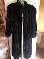 Full view of the dark brown, full-length vintage mink coat hanging on a hanger.