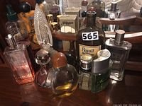 Group shot of assorted perfume and cologne bottles including Royall Parfum, decorative overlay bottle, pressed glass bottle, spray bottles and metal flasks