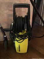 Front view of the yellow Karcher 502MS pressure washer showing the coiled hose and power cord.