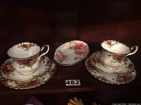 Two Royal Albert Old English Roses tea cups on matching saucers with a small Royal Albert American Beauty oval tray in the center.