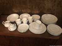Full view of the partial dinnerware set, showing plates, cups, saucers, creamer and sugar bowl arranged on table.