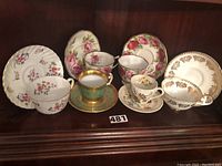 Photo of six English teacups and saucers arranged together showcasing various floral patterns and gold accents