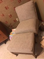 Slipper chair and ottoman positioned side by side on carpeted floor showing fabric texture and wooden legs.