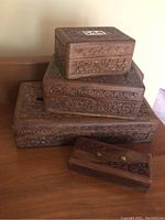 Photo of stacked four carved teak boxes showing floral carving details on all sides.