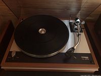 Front view of turntable on wooden plinth with rubber mat and tonearm