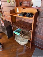 Solid pine four-shelf bookcase displaying scratches and wear, with items placed on shelves against wood-paneled wall.