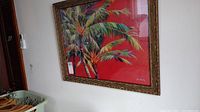 Framed palm tree print on wall with faux bamboo frame visible, signature visible in lower right corner.