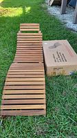 Assembled wood slatted chaise lounge and boxed unit on grass