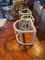 Photo showing the set of three white-painted rattan nesting side tables with glass tops from an overhead angle, highlighting the size difference and nesting arrangement.