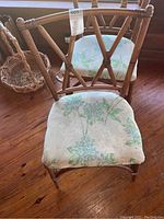 Front view of two rattan dining chairs with floral upholstered cushions on hardwood floor